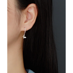 Close-up of S925 sterling silver hoop earrings with sparkling butterfly charms on ear