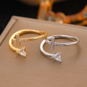 Close-up of gold and silver layered open rings with cross and triangle zircon stone