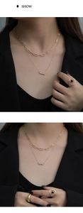 Detailed view of layered gold necklace set with black gemstone rings on a model