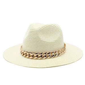 Detail of a chic cream straw fedora hat featuring a bold gold chain link band accent