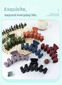 Close-up of matte wave-shaped hair claws in six muted colors on a cozy home background