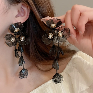 Detailed close-up of long black mesh flower drop earrings with sparkling center crystals