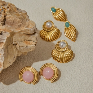 Detailed view of vintage gold stud earrings with pink, pearl, and turquoise accents