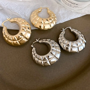 Close-up of gold and silver textured hoop earrings with a vintage wrinkled metal finish
