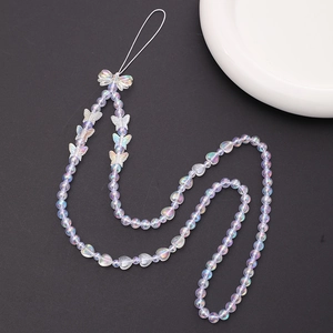 Iridescent beaded phone charm with bow and heart accents on a sleek black surface