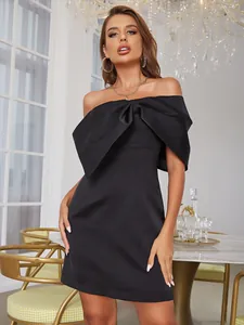 Détail du nœud 3D géant sur une robe courte ajustée en satin noir à épaules nues