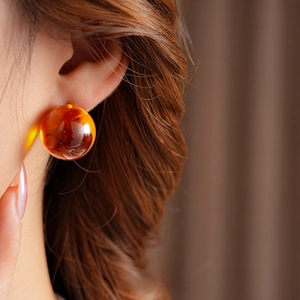 Macro view of vintage amber resin ball earrings with natural internal texture on model