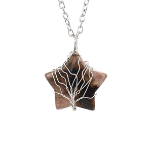 Macro shot of brown crystal star pendant with silver wire-wrapped tree of life design