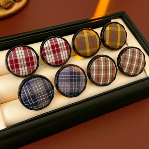 Detailed view of colorful Scottish plaid fabric stud earrings in a premium display box