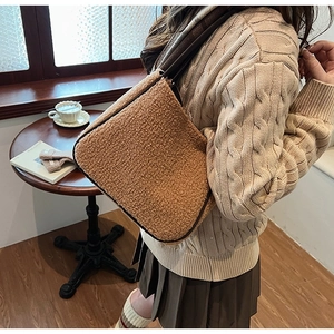 Brown faux shearling tote bag styled with a beige cable-knit sweater in a warm cafe setting