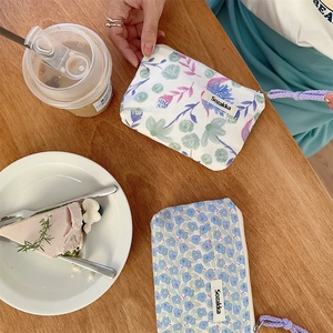 Dettaglio pochette floreale in tela con cerniera metallica e cordino viola al caffè