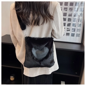 Dettaglio della borsa a tracolla in pelliccia sintetica nera con cuore decorativo