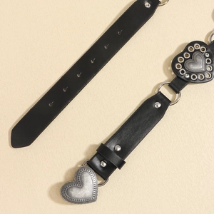 Detail of black leather belts with silver heart-shaped buckles and metal ring accents