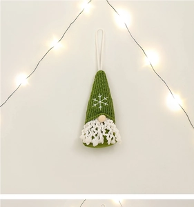 Close-up of green knitted Christmas gnome ornament with white snowflake and plush beard