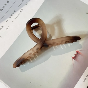 Close-up of a large amber matte hair claw clip on a magazine with soft shadows