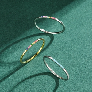 Three minimalist S925 silver rings with turquoise and rainbow stones on green texture