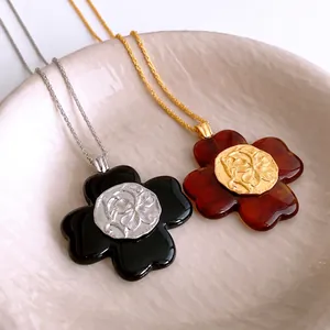 Vintage resin flower pendant necklaces in black and amber with carved metal centerpieces