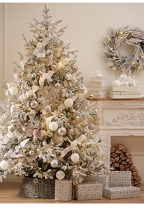 Close-up of champagne gold Christmas balls and lace ribbons on a flocked snow tree
