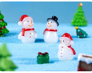 Close-up of miniature glowing snowman set with festive gift boxes and small trees
