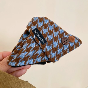 Close-up of a triangle hair claw clip featuring brown plaid fabric and a handmade label