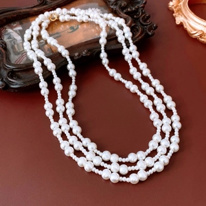 Elegant three-layer white pearl necklace with gold clasp on vintage leather background