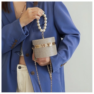 Close-up of golden rhinestone cylinder evening bag with pearl handle and metal chain