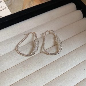 Macro detail of silver twisted hoop earrings with polished and frosted dual-texture finish