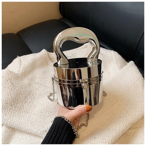 Detailed close-up of a silver mirror-finish cylinder evening bag with a sleek artistic handle