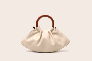 Detail of ruched cream cloud bag with brown round handle on minimalist background
