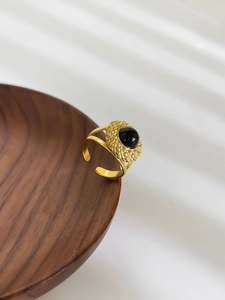 Close-up of vintage 18K gold ring with black oval stone inlay and textured detail