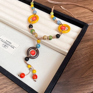 Close-up of ethnic handmade necklace with colorful ceramic beads and woven rope in a gift box