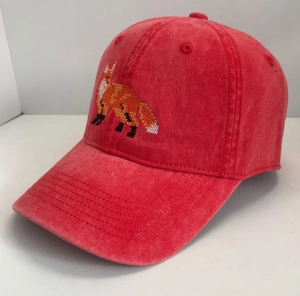 Close-up of vintage washed red baseball cap featuring pixelated fox embroidery on front