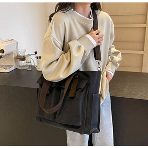 Close-up of black canvas tote bag with brown straps and functional external pockets