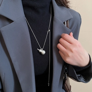 Dettaglio della collana con ciondolo a zucca in argento opaco su dolcevita scuro