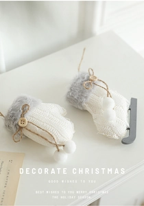Detail of white knit Christmas glove and sock ornaments with wooden buttons and faux fur