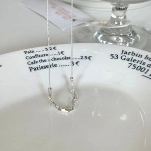 Minimalist 925 sterling silver chain necklace with geometric slider beads on a white plate