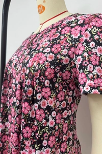 Detail of floral printed short sleeve top with round neck pleats and pink blossoms