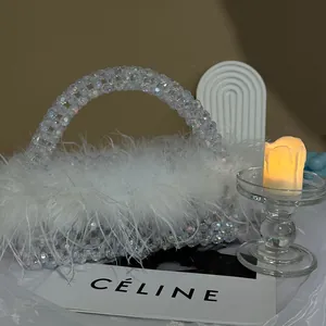 Detail of handcrafted beaded handbag featuring fluffy white ostrich feathers for evening wear