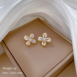 Detailed macro view of gold clover stud earrings with clear zircon petals and weight info