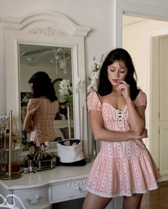 Detail of pink floral mini dress with lace trim and puff sleeves in a lifestyle setting
