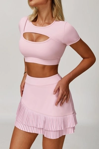 Dettaglio del crop top rosa da yoga con taglio sul petto e gonna da tennis a pieghe abbinata