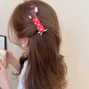 Close-up of a plush dachshund hair clip with red polka dot shirt on long wavy hair