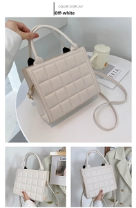 Close-up of cream white quilted handbag with twin handles and fine shoulder strap detail