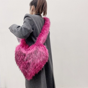 Detail of rose pink heart-shaped faux fur crossbody bag worn by a model