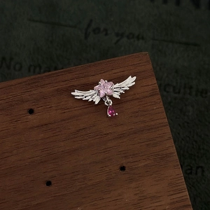 Detailed close-up of wing star earring with pink gemstone and red drop pendant