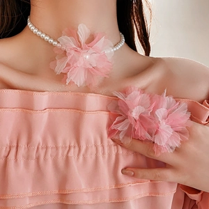 Detail view of pink chiffon flower pendant on a dainty white pearl necklace and matching ring