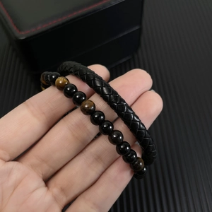 Detail showing red tiger eye beads and braided black leather bracelet for men