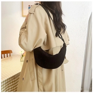 Detailed view of a black corduroy dumpling bag worn by a model in a casual setting