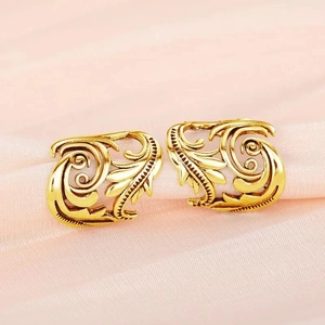Detailed macro view of vintage hollow leaf pattern ear cuffs in bright golden finish