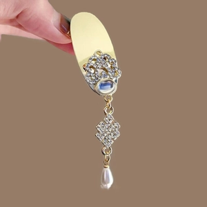 Detail of golden finger ring armor featuring sparkling rhinestones and a drop pearl pendant